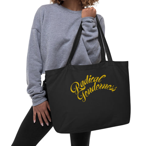 Front view of black tote with Radical Tenderness embroidered in gold cursive letters.