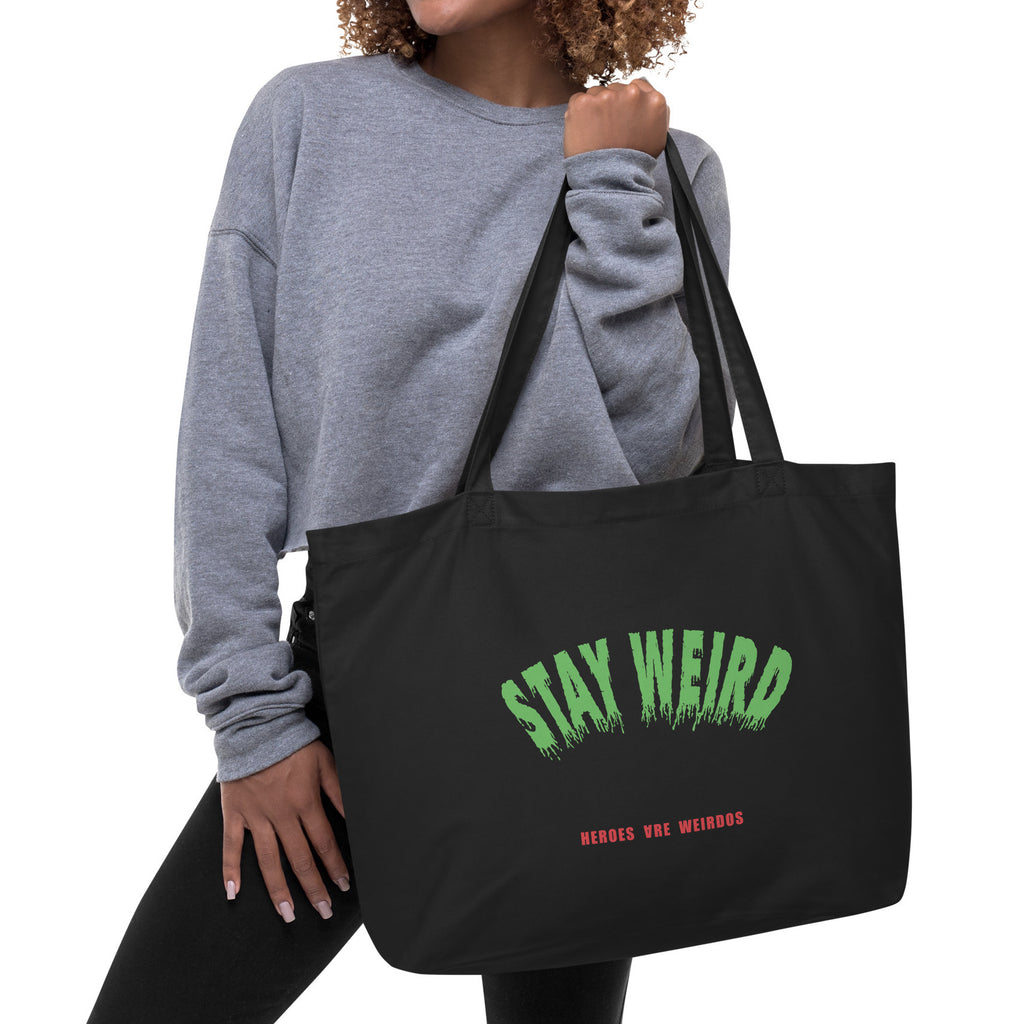 Person holding a black tote with Stay Weird printed in green